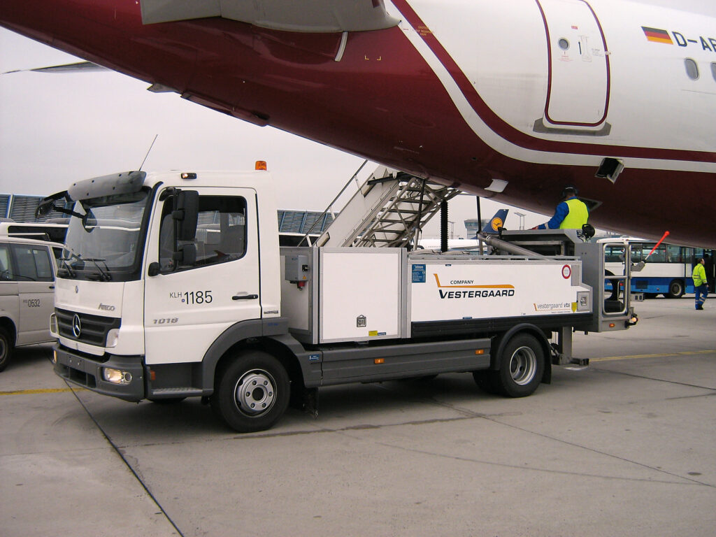 Mercedes-Benz fuel truck servicing an aircraft on the tarmac, with personnel using a ladder for access.