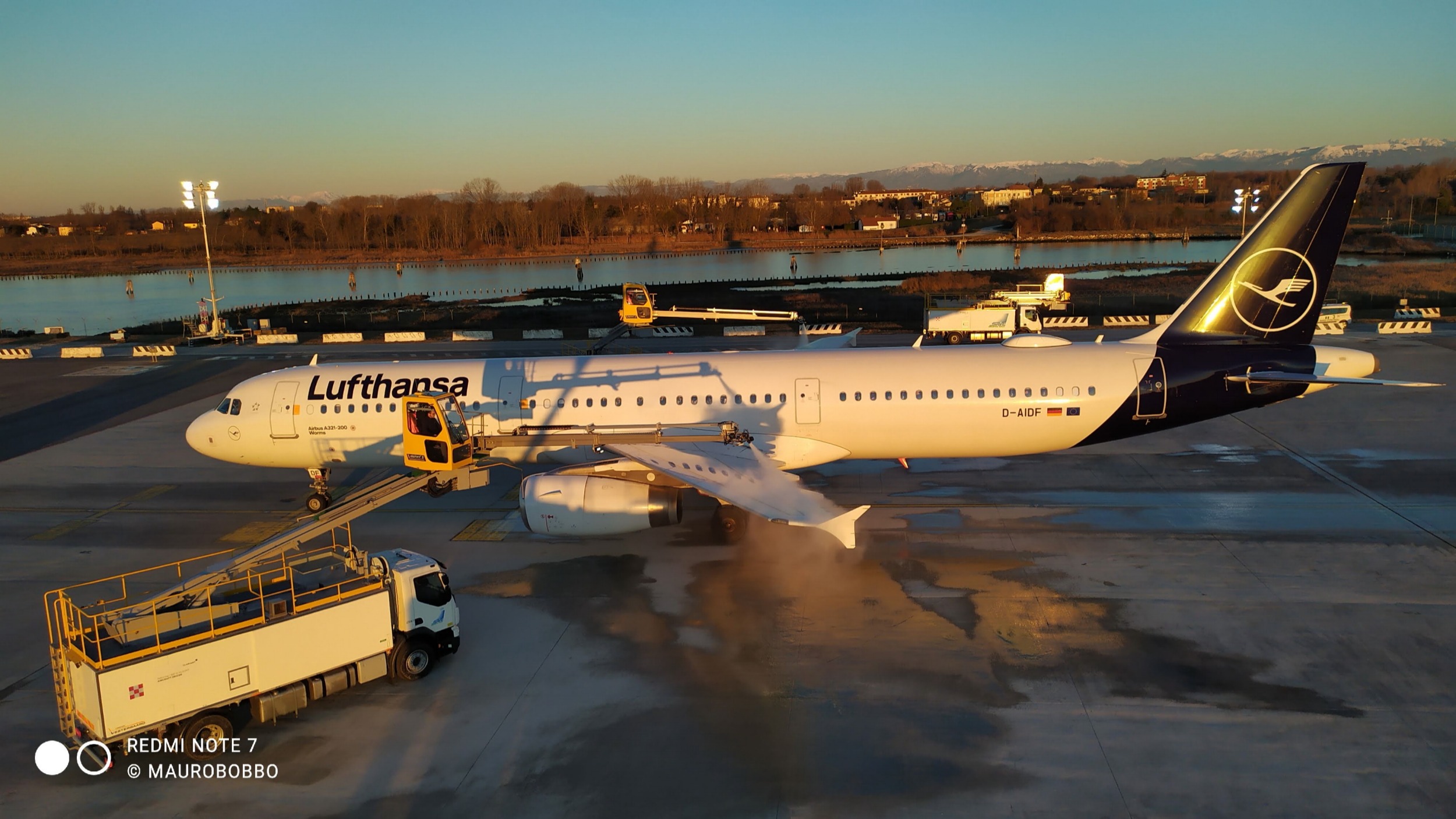 Lufthansa airplane D-AIDF at the airport with a yellow service vehicle preparing for maintenance.